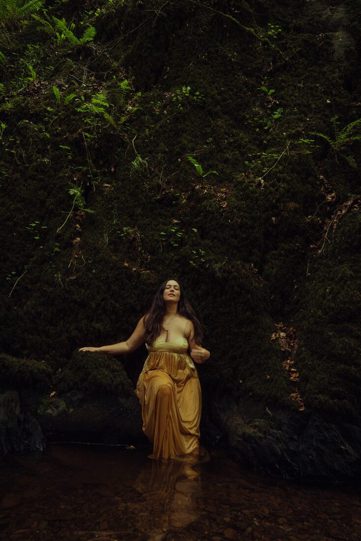 Natalie in the stream beneath the mossy falls