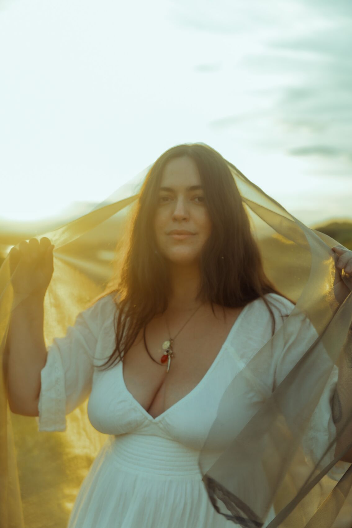 Natalie holding a golden veil to the sun