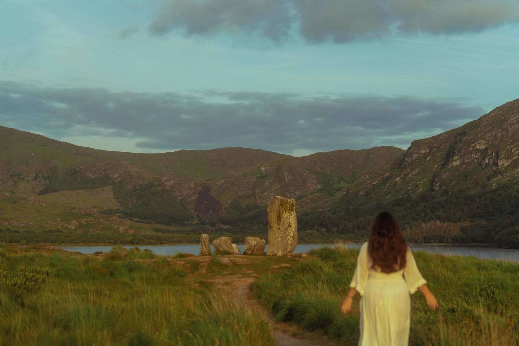 Natalie walking toward the standing stones at golden hour