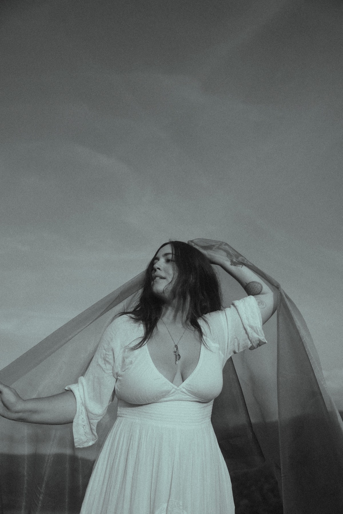 Natalie in white, raising her veil to the sky